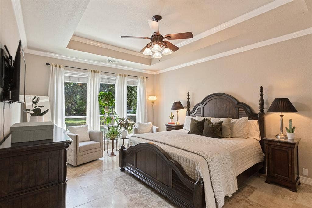 214 Stanford Ct. - Spacious primary bedroom featuring travertine flooring, tray ceiling, ceiling fan, and beautiful windows overlooking the backyard and pool.