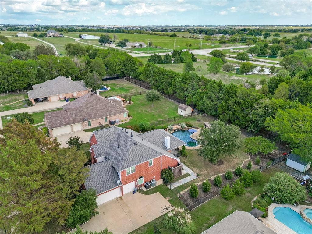 214 Stanford Ct. - Aerial view showcasing the three-car garage, expansive backyard with resort-style pool, Heath Golf & Yacht Club golf course beyond the trees, and picturesque surrounding countryside.