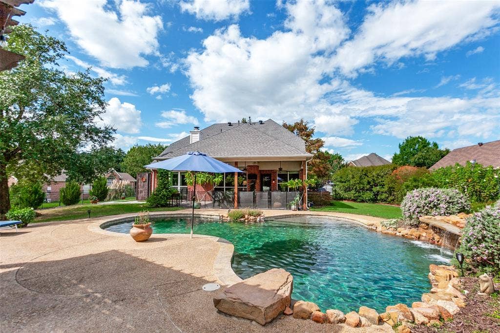214 Stanford Ct. - Resort-style pool with waterfall feature and diving rock, surrounded by beautiful landscaping, pergola, and ample space for outdoor entertaining and sunbathing.