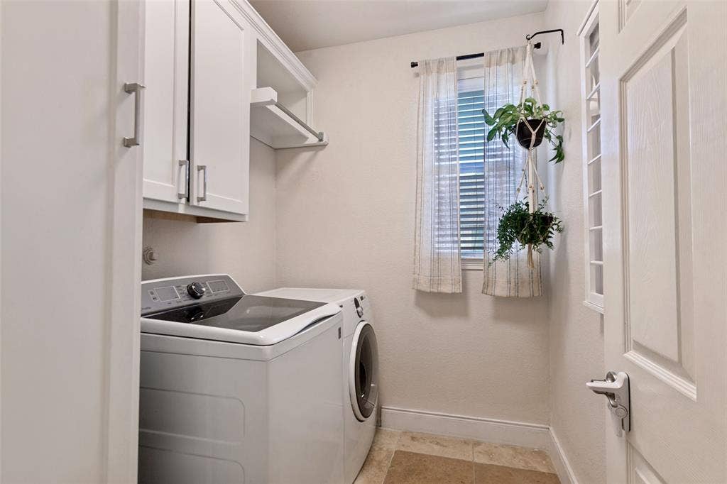 214 Stanford Ct. - First-floor laundry room featuring travertine tile flooring, abundant built-in storage, hanging and drying racks, and a window for natural light.