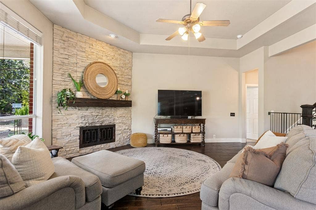 214 Stanford Ct. - Inviting living room featuring a stacked-stone gas starter fireplace with wood mantel, hardwood floors, and ceiling fan.