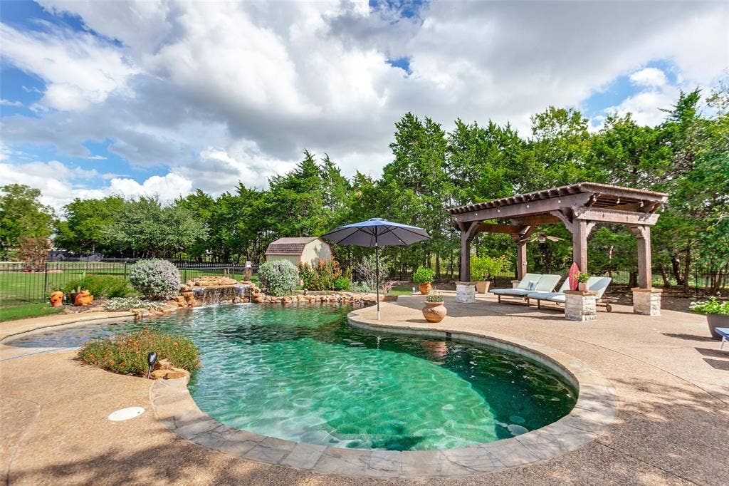 214 Stanford Ct. - Resort-style pool with waterfall feature and diving rock, surrounded by beautiful landscaping, pergola, and ample space for outdoor entertaining and sunbathing.