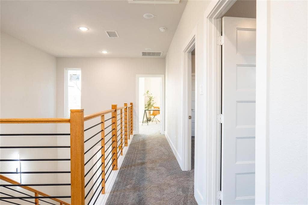 Hallway featuring carpeting, recessed lighting, and a stair railing composed of wood posts with horizontal metal balusters, accompanied by five-panel interior doors