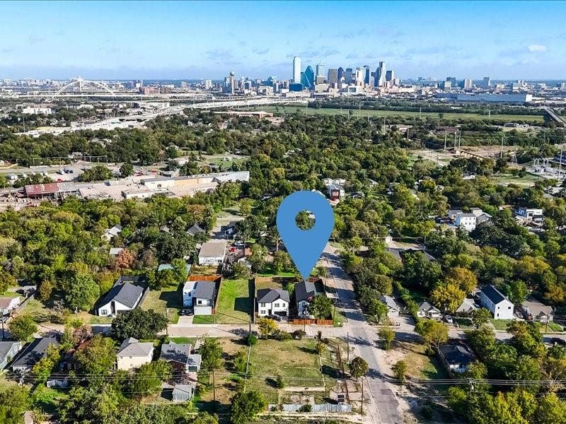 Aerial perspective featuring a standalone property with a pitched roof, exterior wood fencing, and a proximity to an urban skyline