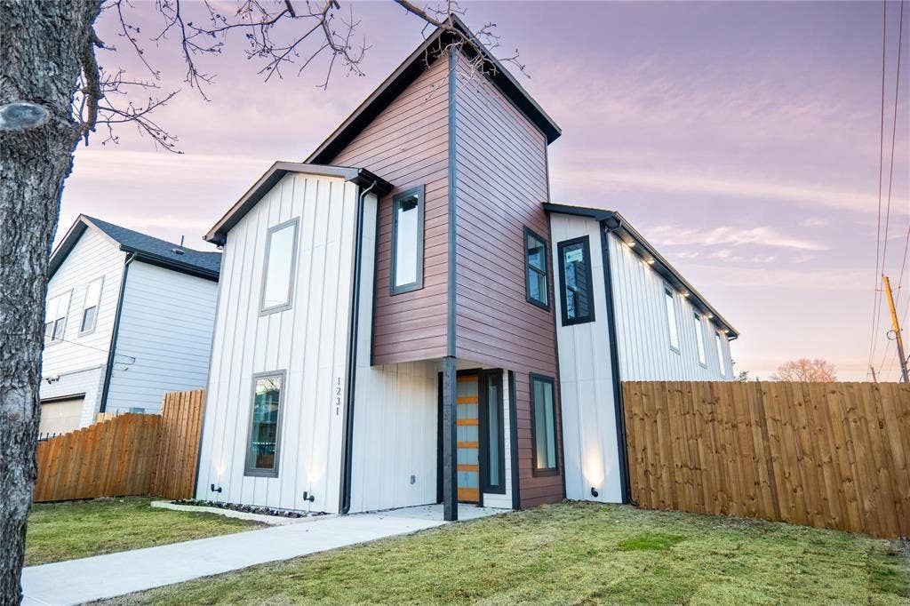 Modern exterior featuring vertical board-and-batten siding, horizontal wood-finish accents, tall rectangular windows, and recessed lighting