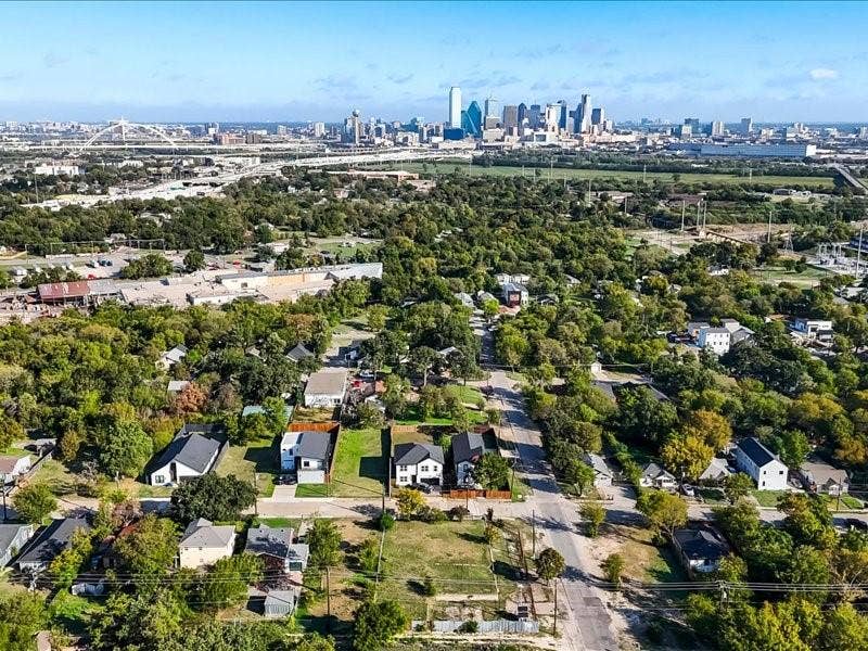Aerial perspective showcasing an urban residential setting featuring mature trees and a prominent city skyline backdrop