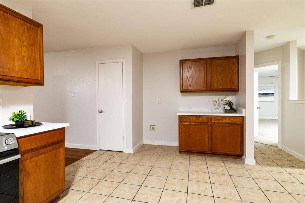 Kitchen featuring wood cabinetry, white countertops, tile flooring, and a dedicated storage closet