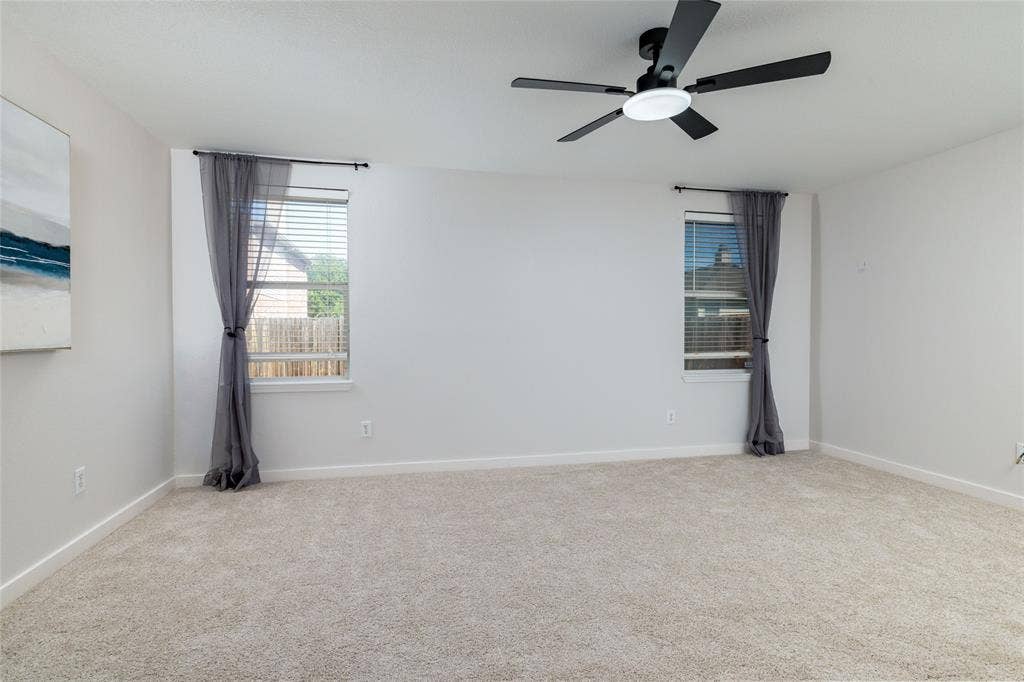 Neutral-toned wall-to-wall carpeting, black multi-blade ceiling fan with integrated lighting, dual windows with integrated blinds, and light-toned wall finish