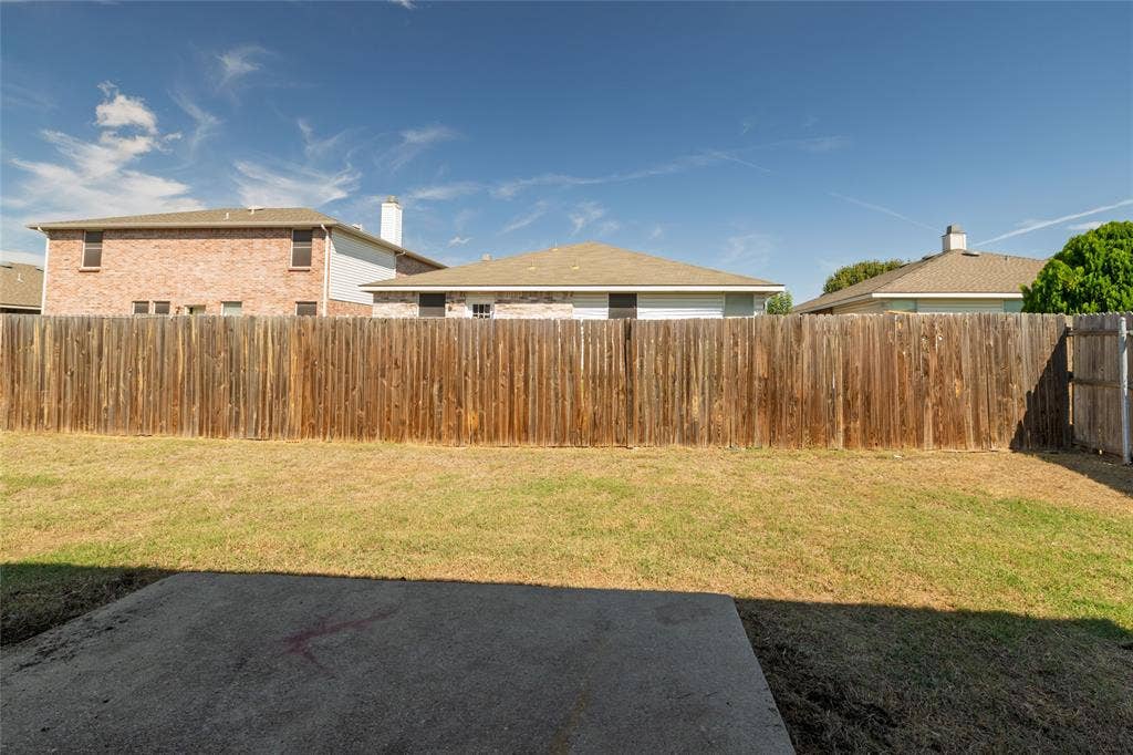 Fenced backyard featuring a concrete patio and a lawn