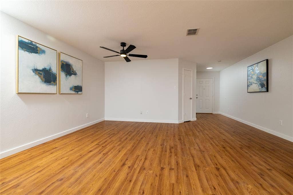 Neutral interior featuring wood-finish flooring, recessed ceiling lighting, and a black matte ceiling fan