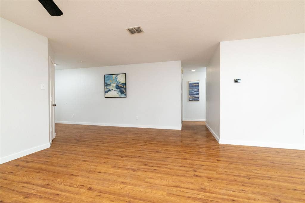 Open-concept interior featuring wood-finish flooring, neutral walls, and a ceiling-mounted fan