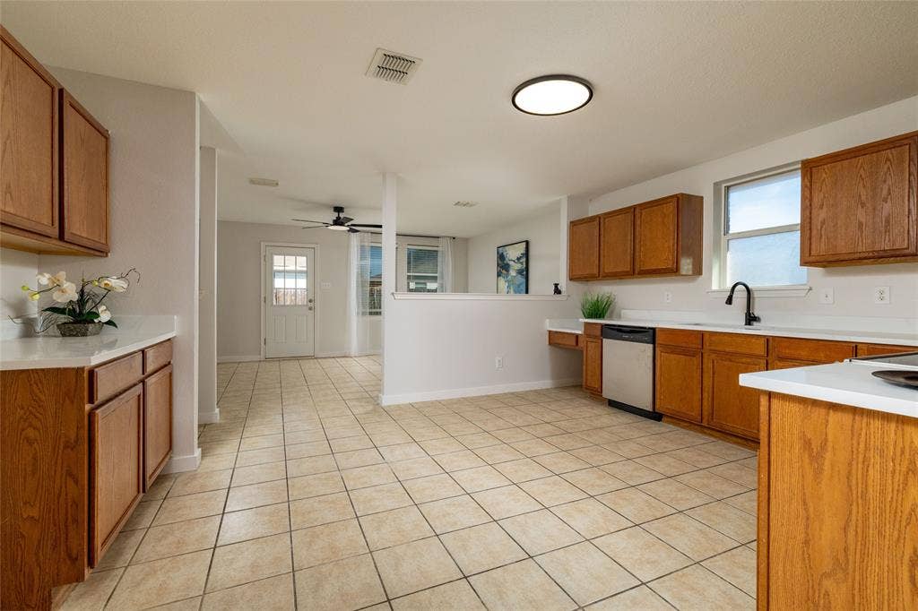Kitchen featuring solid wood cabinetry, white countertops, tile flooring, stainless steel dishwasher, and matte black kitchen faucet