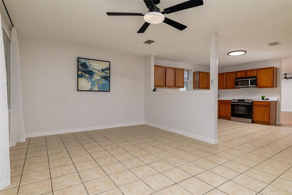 Ceramic tile flooring, neutral wall tones, kitchen featuring wood cabinetry, stainless steel appliances, and ceiling fan with integrated lighting