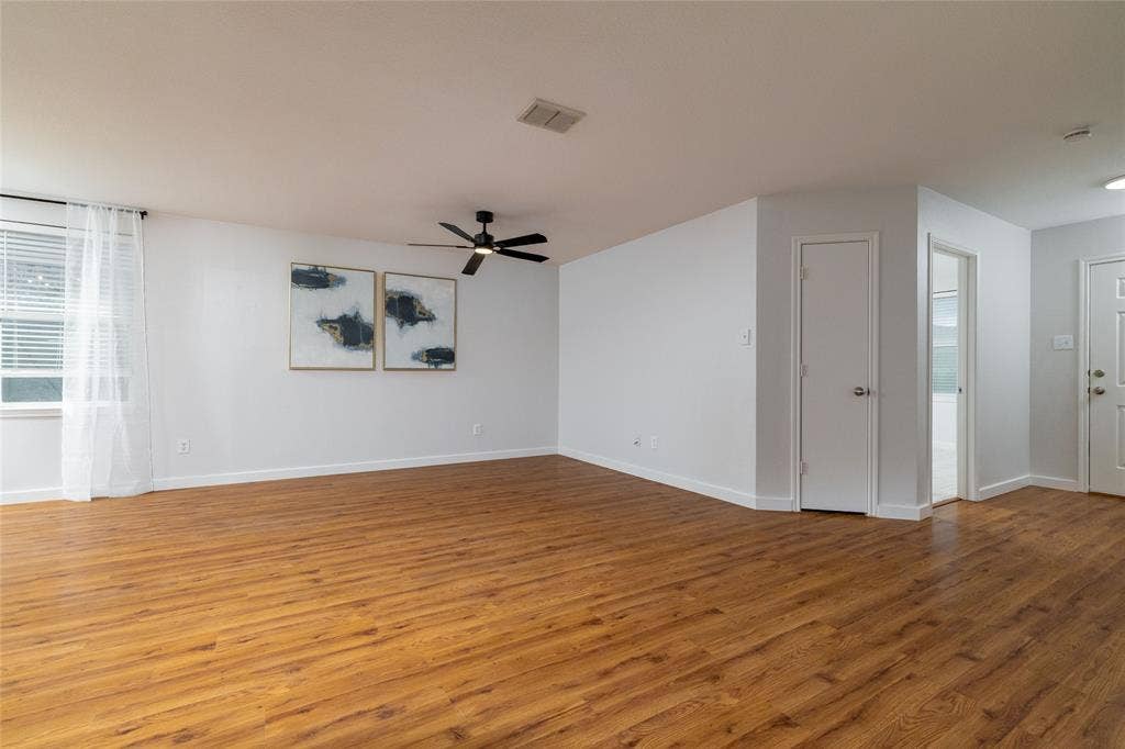 Open floor plan featuring wood-finish flooring, neutral wall paint, and a ceiling-mounted fan with integrated lighting