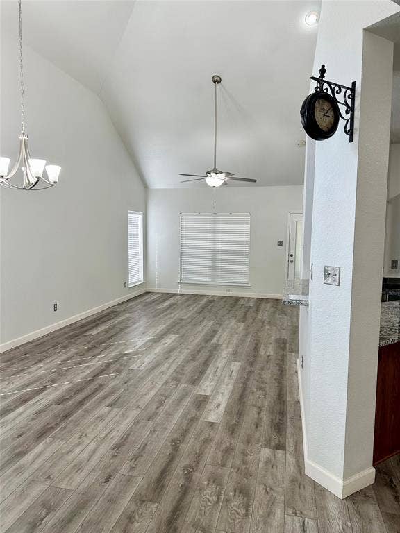 9756 Old Field Drive, McKinney, TX 75072 Vaulted ceiling featuring a central ceiling fan with integrated light, wood-finish flooring, and multi-arm chandelier lighting
