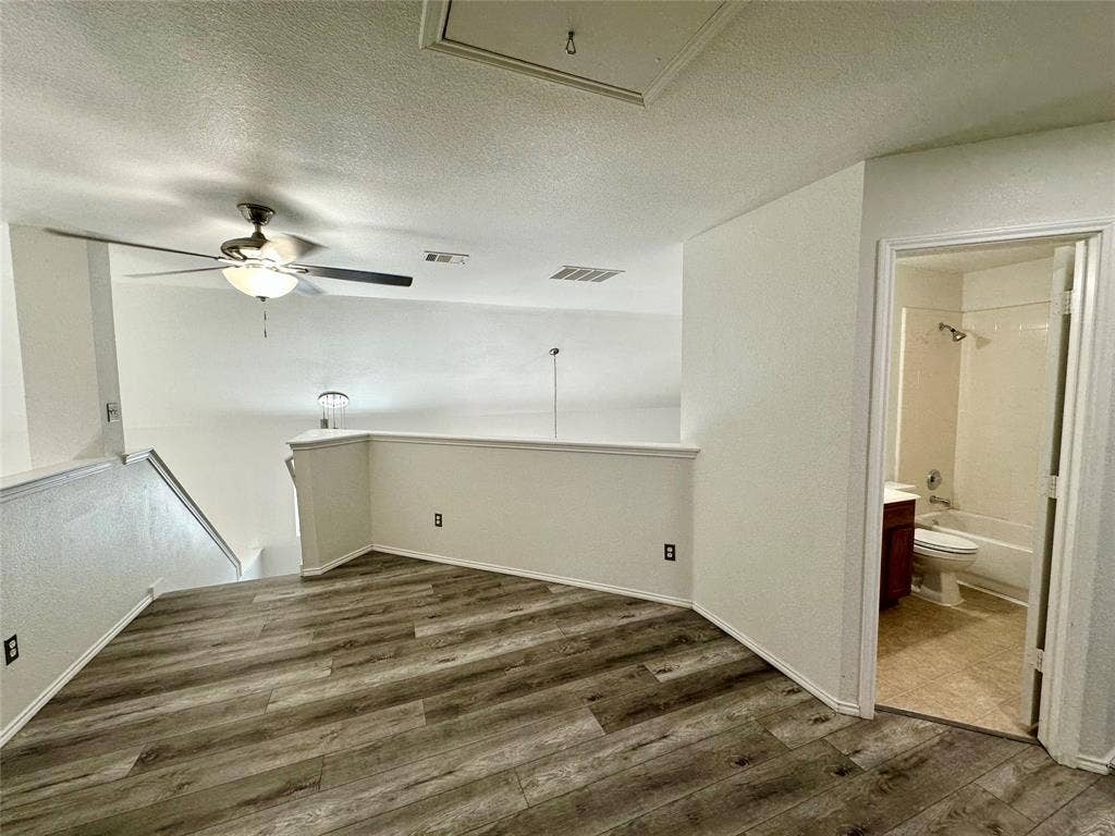 9756 Old Field Drive, McKinney, TX 75072 Open loft area featuring wood-finish flooring, ceiling fan with integrated lighting, and access to a full bathroom with a combination tub and shower