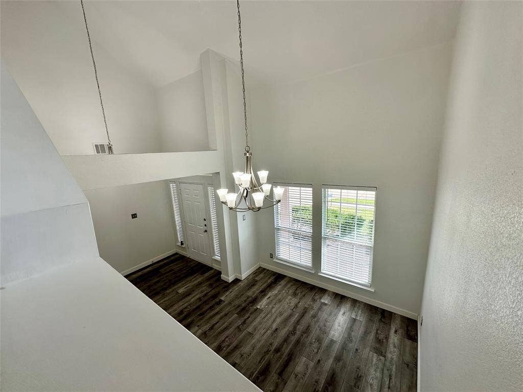 9756 Old Field Drive, McKinney, TX 75072 High-ceiling interior featuring wood-finish flooring, a multi-arm chandelier, and large windows with horizontal blinds