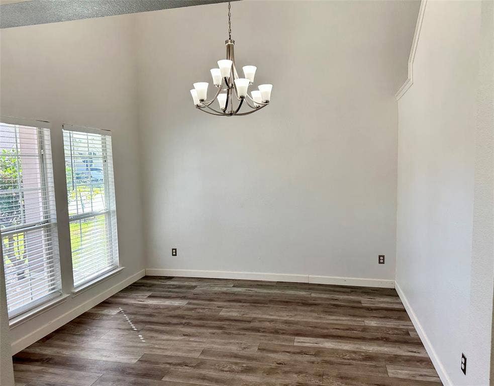 9756 Old Field Drive, McKinney, TX 75072 Vaulted ceiling, wood-finish flooring, multi-light brushed-nickel chandelier, and dual tall windows with horizontal blinds