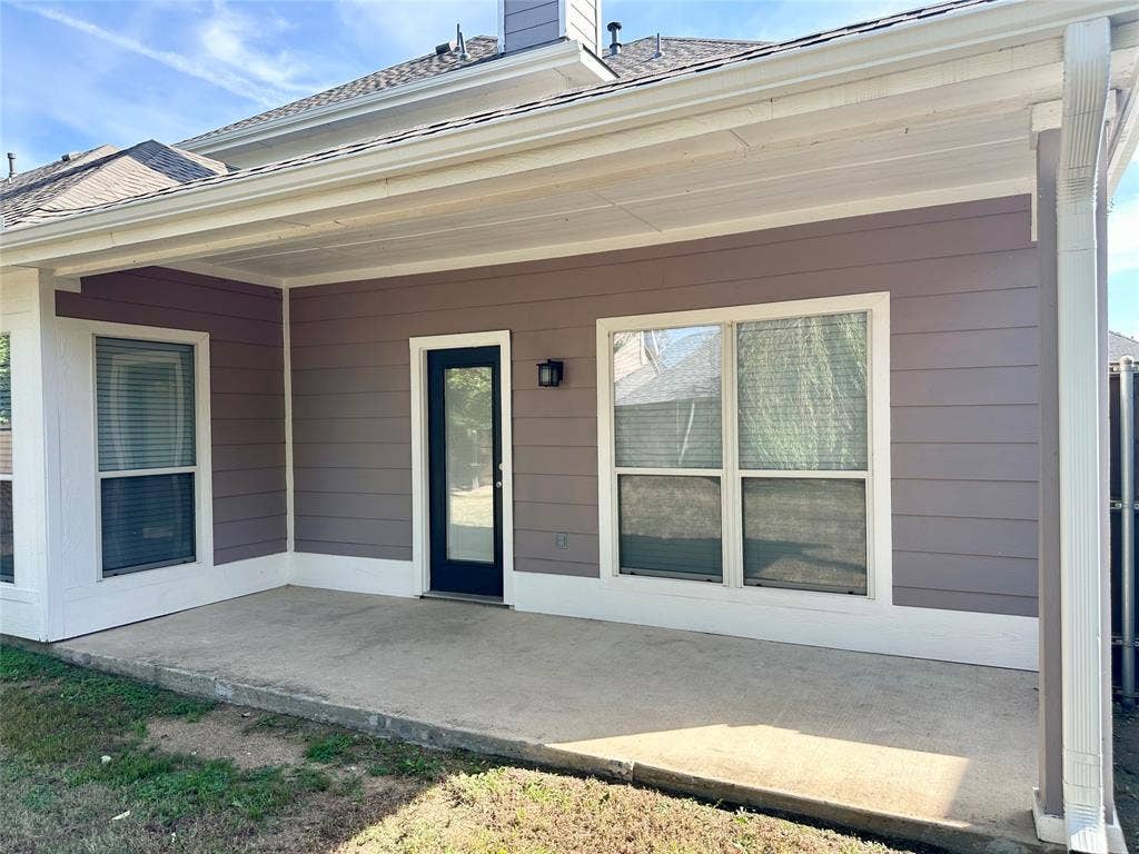 9756 Old Field Drive, McKinney, TX 75072 Covered concrete patio featuring horizontal siding, exterior wall-mounted lighting, and a glass-paneled door