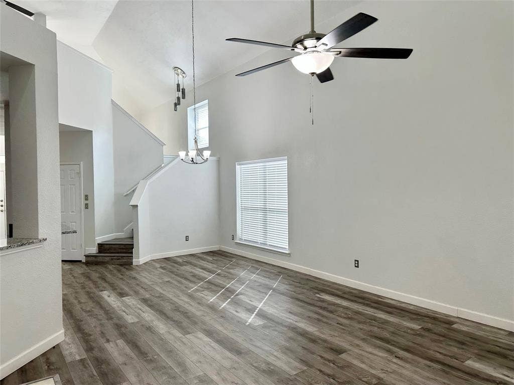 9756 Old Field Drive, McKinney, TX 75072 Vaulted ceiling featuring a multi-blade ceiling fan with integrated lighting, wood-finish flooring, and dual-level hanging pendant lighting