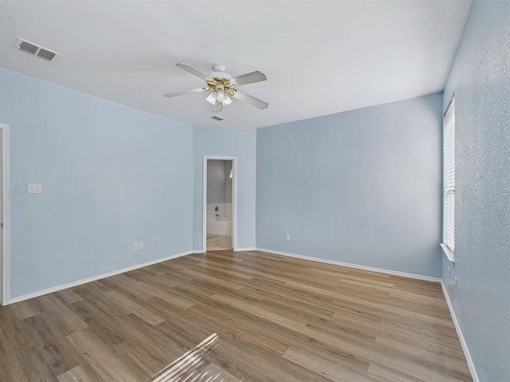 12652 Oakwood Circle, Fort Worth, TX 76040 Spacious room featuring wood-finish flooring, a ceiling fan with integrated light fixture, and large window with blinds