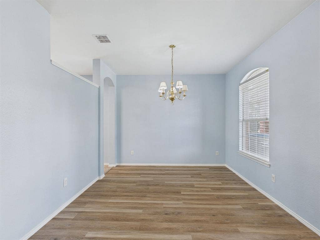 12652 Oakwood Circle, Fort Worth, TX 76040 Room featuring wood-finish flooring, an arched window, and a multi-arm chandelier