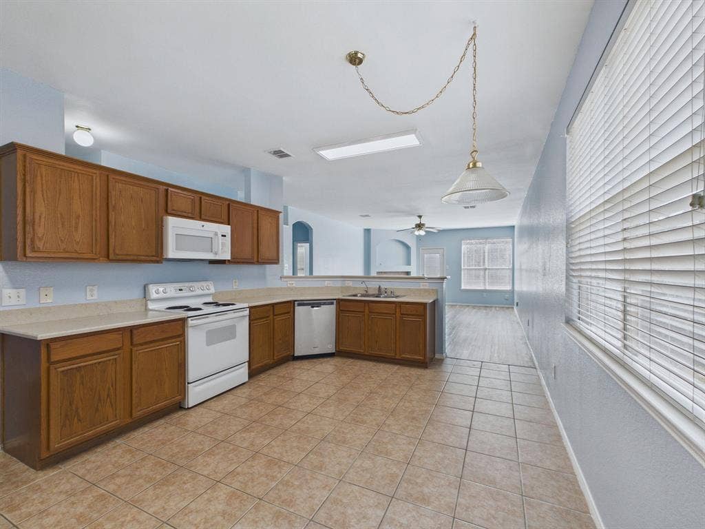 12652 Oakwood Circle, Fort Worth, TX 76040 Kitchen featuring natural wood cabinetry, solid-surface countertops, tile flooring, built-in dishwasher, and a pendant light fixture