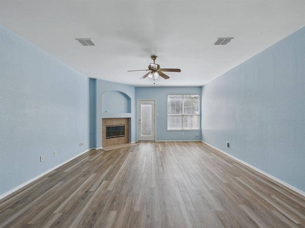 12652 Oakwood Circle, Fort Worth, TX 76040 Wood-finish flooring throughout, fireplace with a stone-surround alcove, ceiling fan with light fixture, and a glass-paneled exterior door