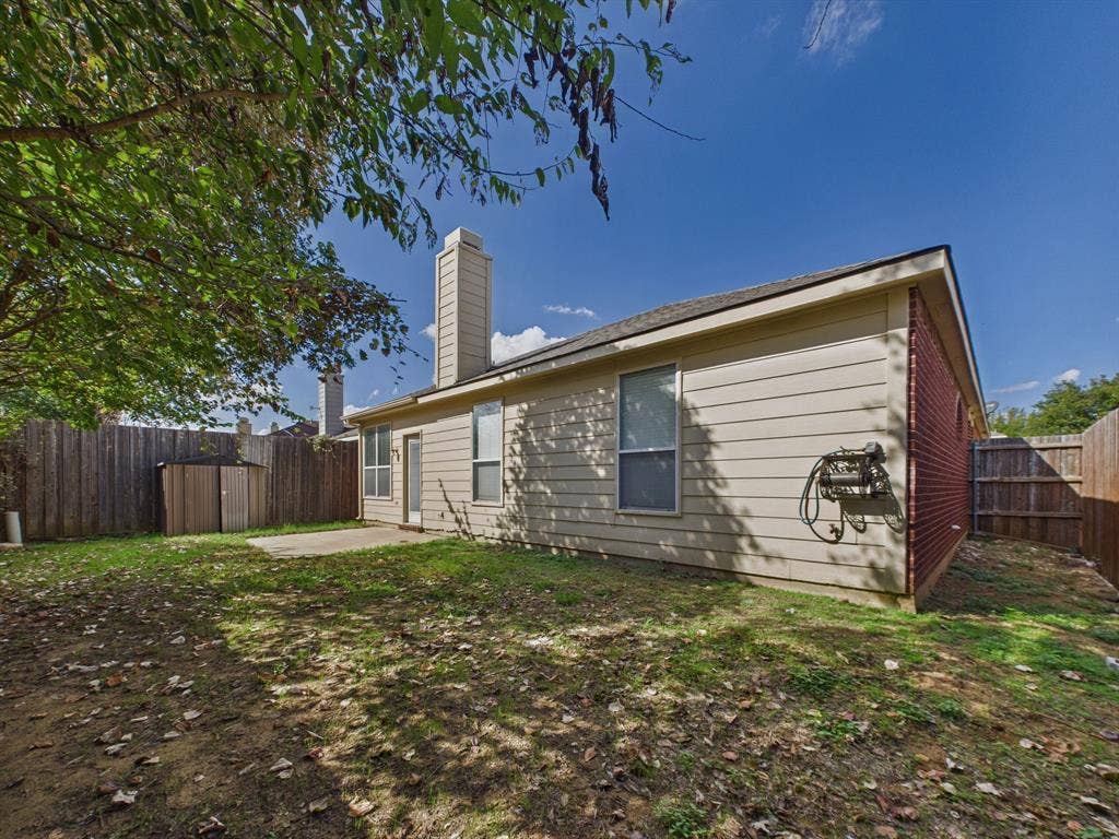 12652 Oakwood Circle, Fort Worth, TX 76040 Exterior featuring a brick and horizontal siding facade, chimney, concrete patio, and wood privacy fencing