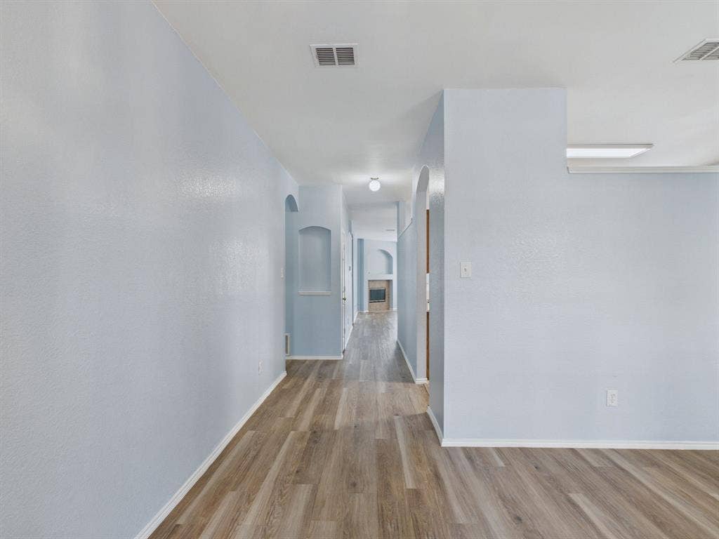 12652 Oakwood Circle, Fort Worth, TX 76040 Interior hall featuring wood-finish flooring, textured wall finishes, arched wall niches, and ceiling-mounted light fixtures