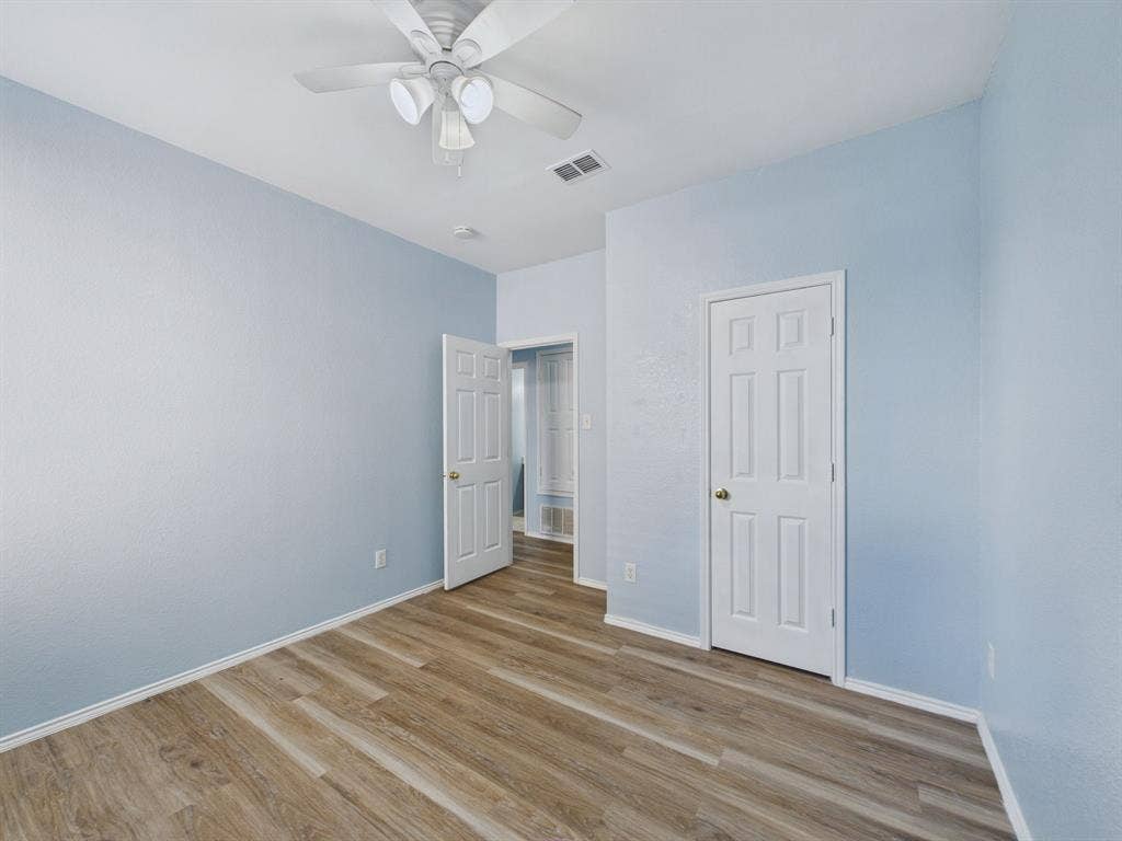 12652 Oakwood Circle, Fort Worth, TX 76040 Interior room featuring wood-finish flooring, a ceiling fan with integrated lighting, and two six-panel interior doors