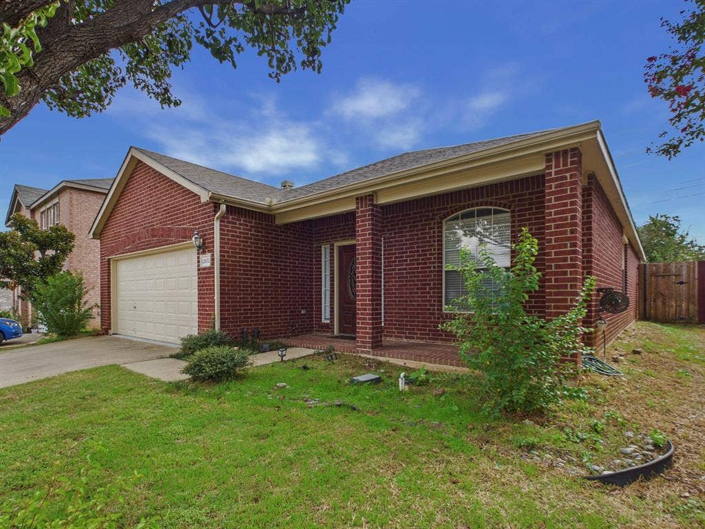 12652 Oakwood Circle, Fort Worth, TX 76040 Traditional brick exterior featuring a covered front porch, arched window detailing, and an attached two-car garage