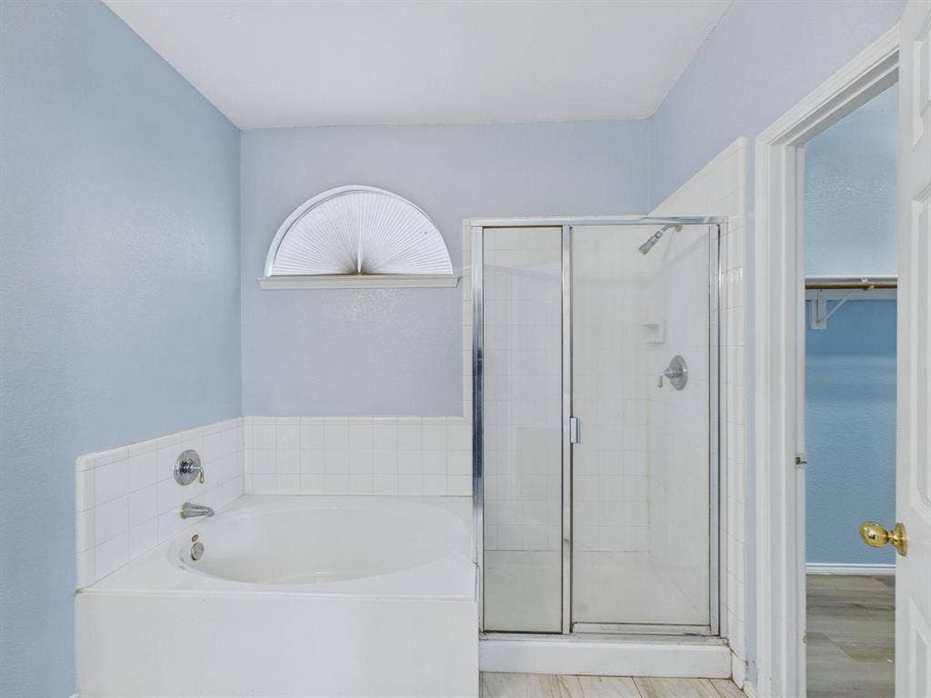 12652 Oakwood Circle, Fort Worth, TX 76040 Deep soaking tub with a tiled surround, glass-enclosed shower, semi-circle window, and bright interior finish