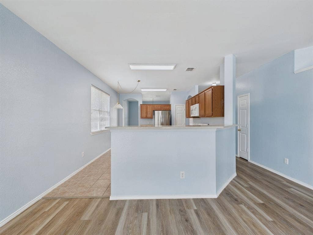 12652 Oakwood Circle, Fort Worth, TX 76040 Kitchen featuring wood cabinetry, stainless steel refrigerator, white tile flooring, wood-finish flooring, and a peninsula counter