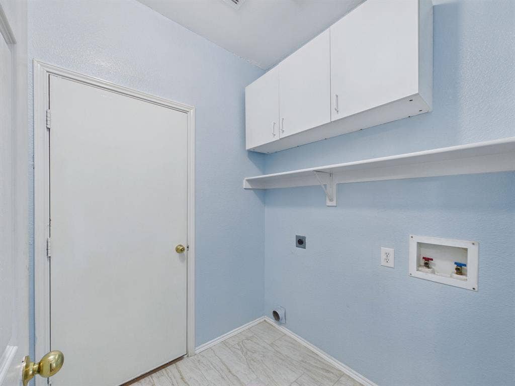 12652 Oakwood Circle, Fort Worth, TX 76040 Laundry area featuring white cabinetry, an open wall-mounted shelf, stone-finish tile flooring, and utility hookups