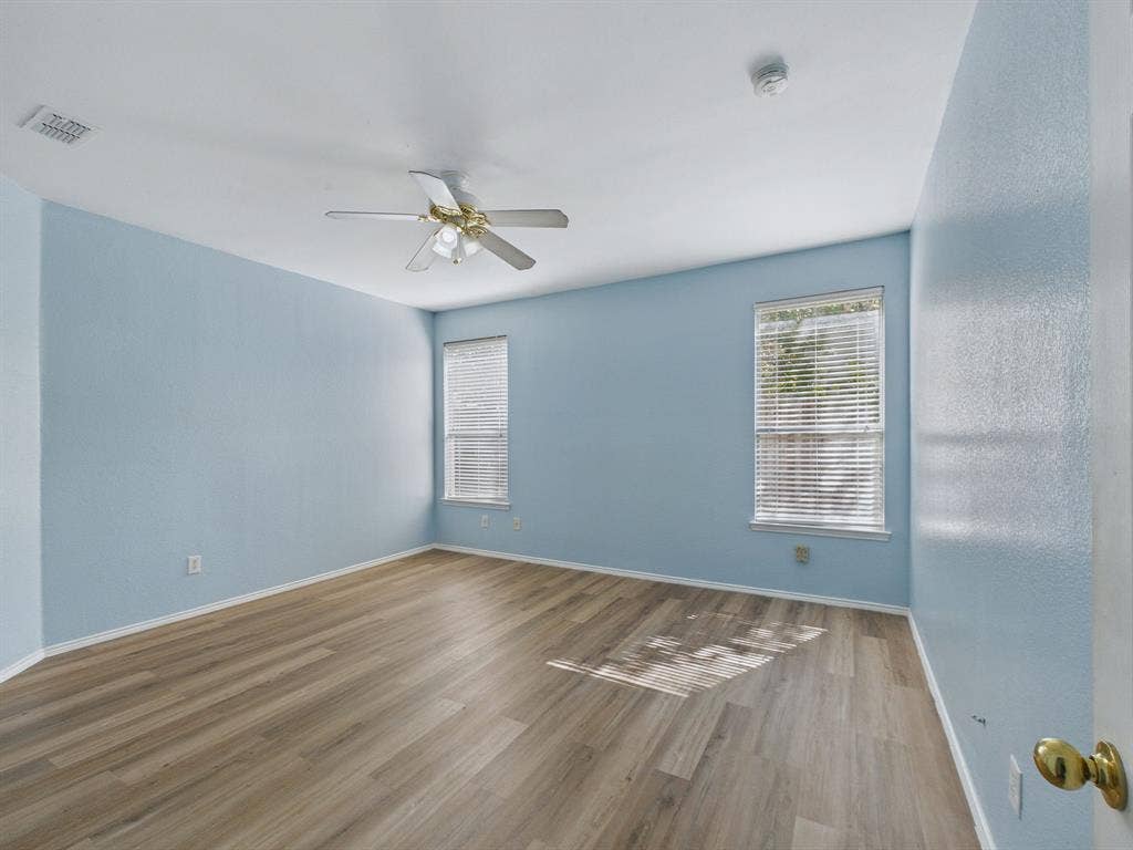 12652 Oakwood Circle, Fort Worth, TX 76040 Room featuring wood-finish flooring, dual windows with blinds, and a ceiling-mounted light fixture with fan