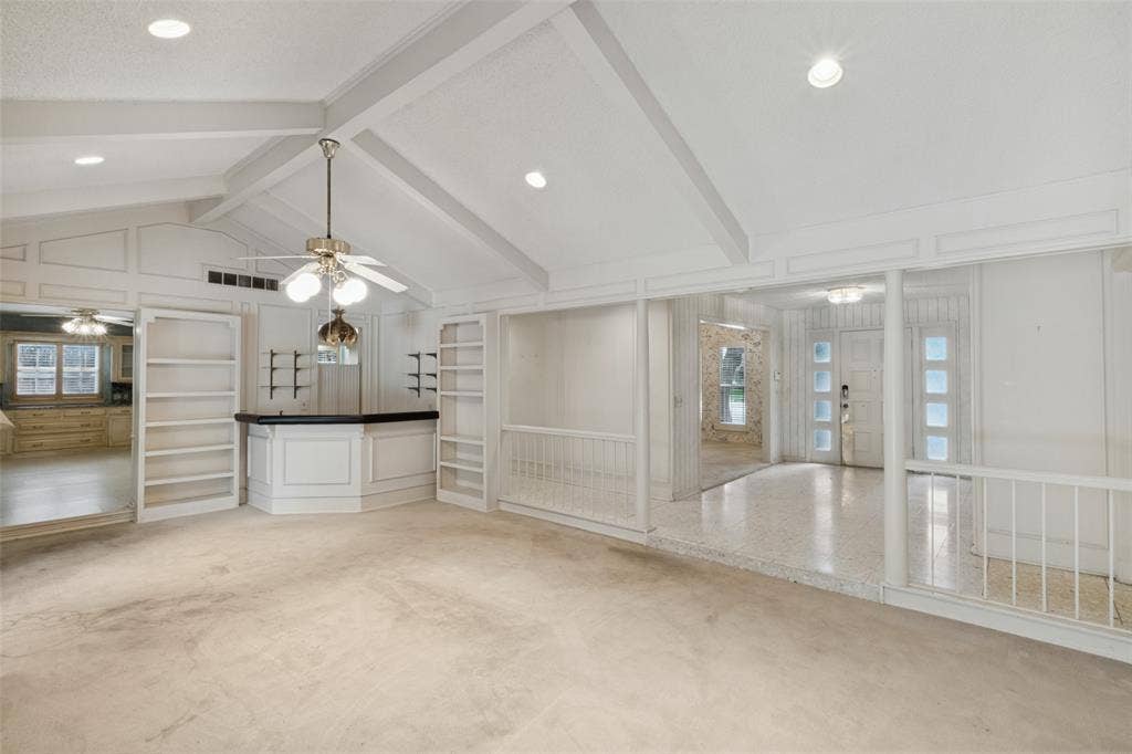 6936 Wildglen Drive, Dallas, TX 75230 Vaulted ceiling with exposed beams, built-in cabinetry, custom wet bar, recessed lighting, and tiered levels with balustrade railings
