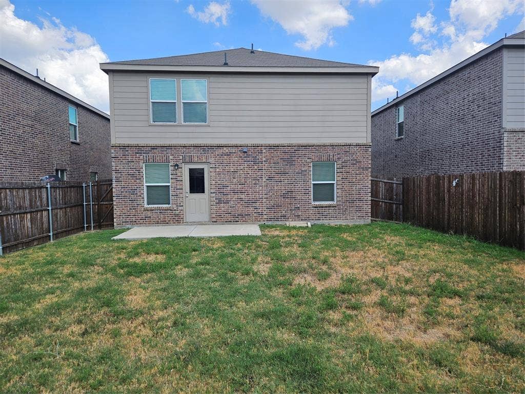 1860 Ballinger Drive, Forney, TX 75126 Rear exterior featuring a brick and siding facade, concrete patio, and fenced-in backyard