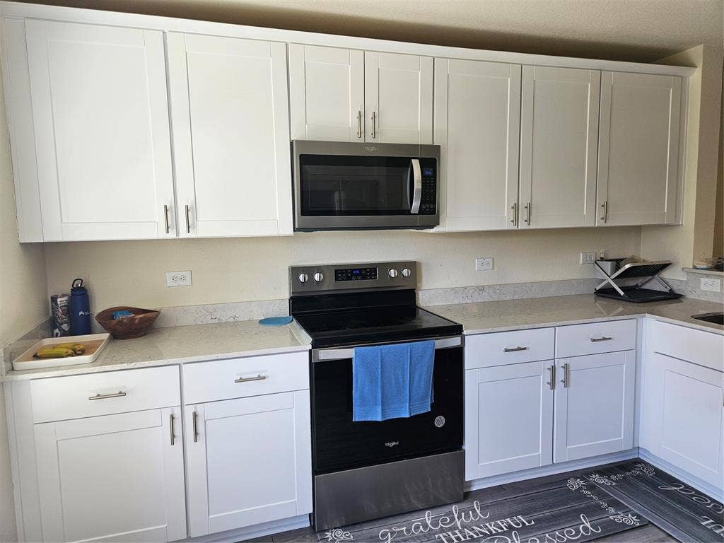 1860 Ballinger Drive, Forney, TX 75126 White shaker-style cabinetry, stainless steel appliances, neutral stone-finish countertops, and wood-finish flooring