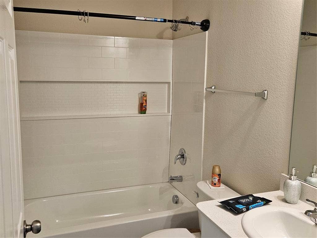 1860 Ballinger Drive, Forney, TX 75126 Full-width bathtub with white subway tile surround, integrated shower niche, light-toned countertop, and undermount vanity sink