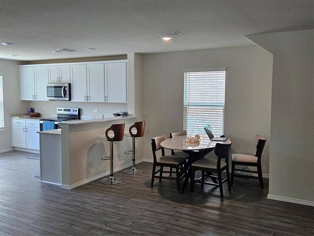 1860 Ballinger Drive, Forney, TX 75126 Kitchen featuring white cabinetry, stainless steel appliances, and a breakfast bar