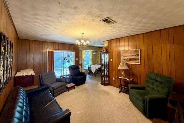 Interior space featuring floor-to-ceiling wood paneling, textured ceiling, multi-light chandelier, and glass sliding door