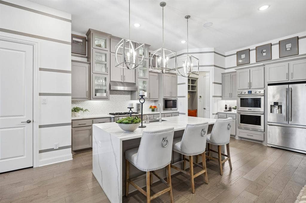 641 Country Brook Lane, Prosper, TX 75078 Stunning gourmet kitchen offers double ovens, waterfall edge Quartz Island, lit cabinets, 6 burner high end cooktop.