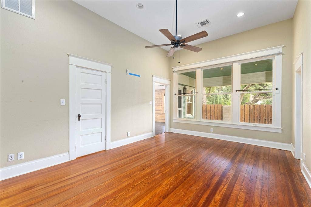 Vaulted ceilings, wood-finish flooring, large multi-pane windows, and a ceiling fan