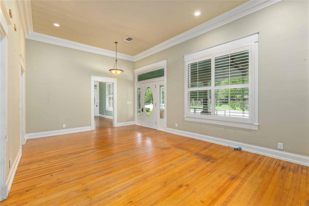 High ceilings with crown molding, wood-finish flooring, plantation shutters, recessed lighting, and a pendant light fixture