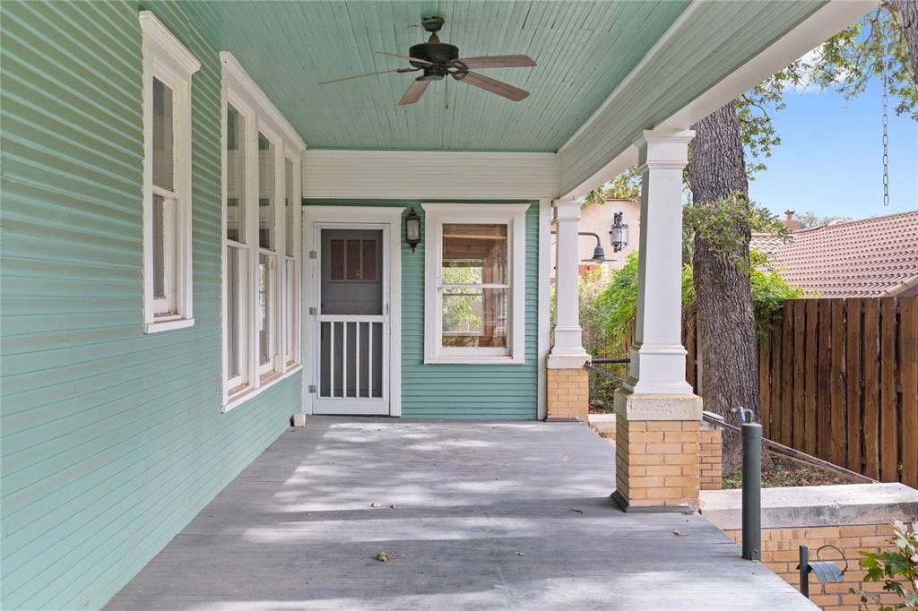 Covered porch featuring lap siding, paneled wood columns with masonry bases, a ceiling-mounted fan, and a wood-frame screen door