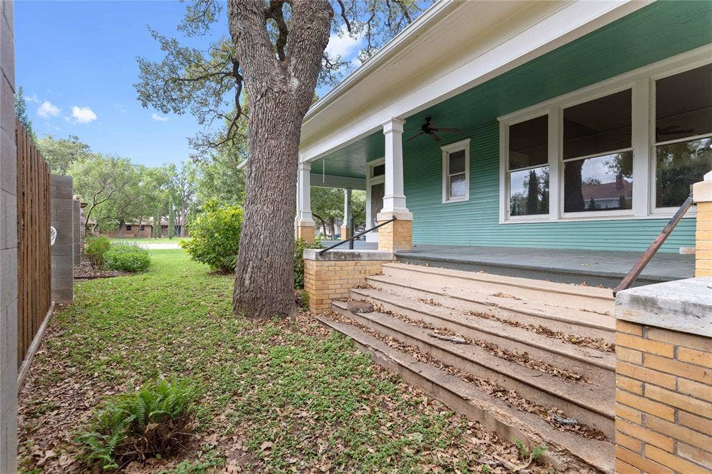 Covered front porch featuring brick piers, painted wood siding, a ceiling fan, and concrete steps