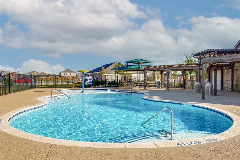 Swimming pool featuring a dedicated water feature, built-in entry steps, metal handrails, and a covered pergola