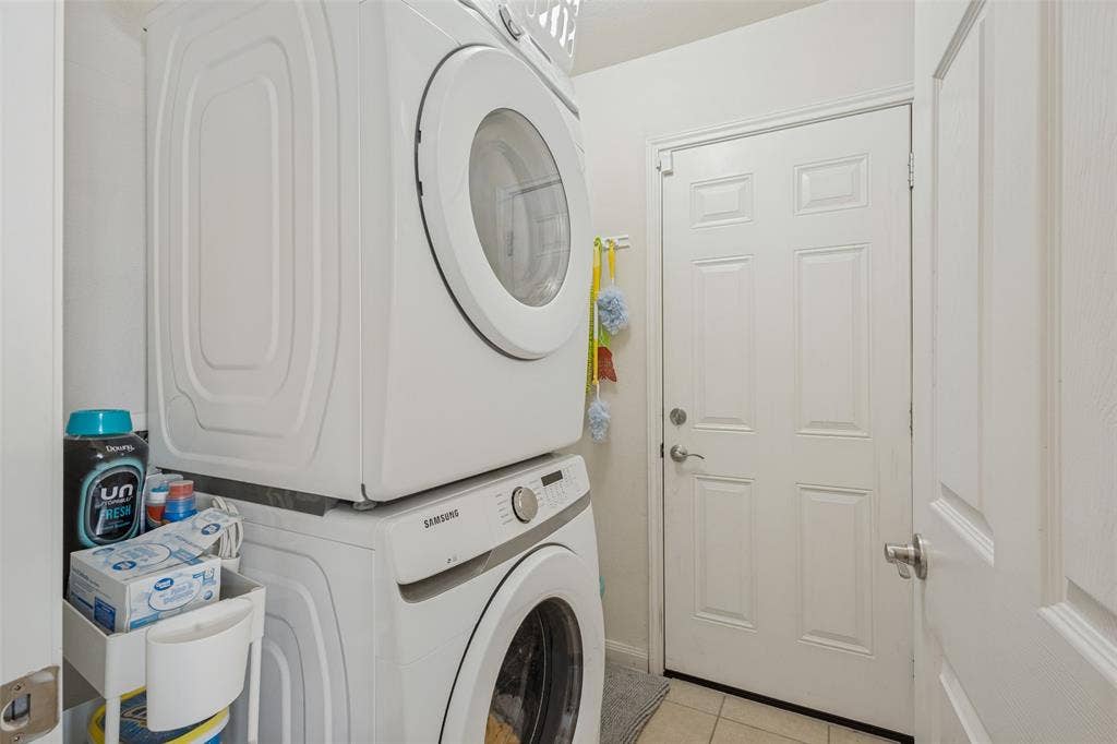 Dedicated laundry area featuring a stacked front-load washer and dryer unit and a six-panel interior door