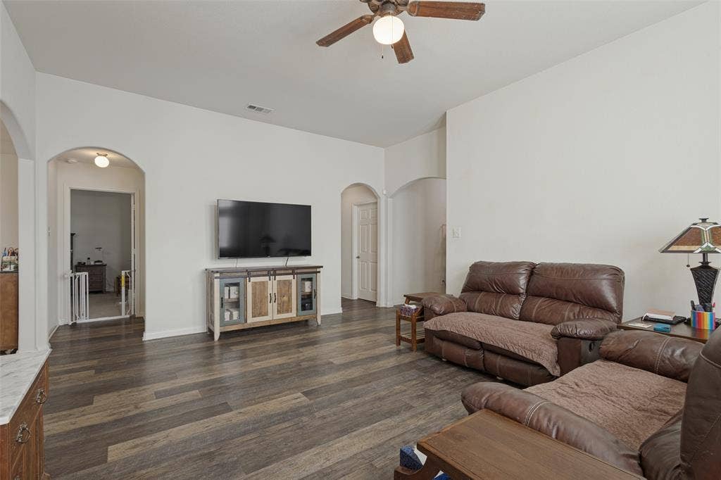 Living area featuring high ceilings, wood-finish flooring, and multiple arched entryways with a ceiling-mounted light fixture
